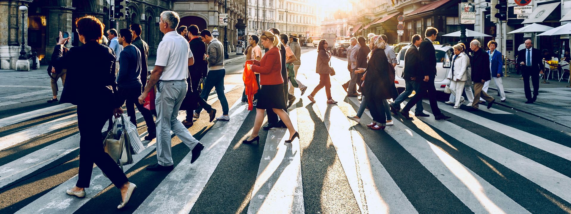 Different people cross a crosswalk in a city.