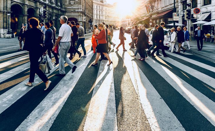 Different people cross a crosswalk in a city.