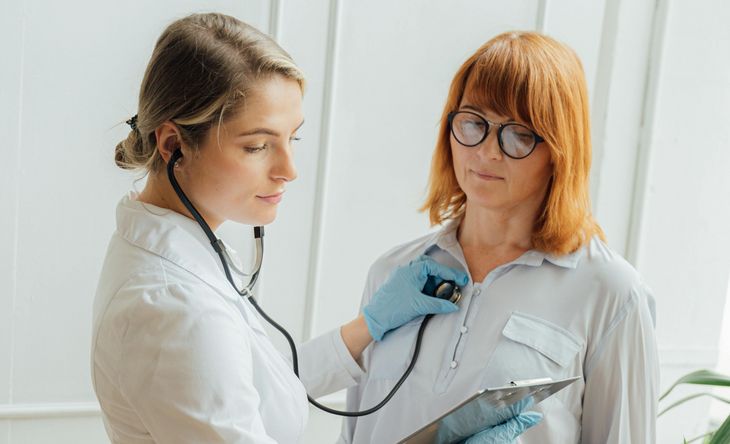 Eine Ärztin untersucht eine Patientin mit dem Stethoskop.