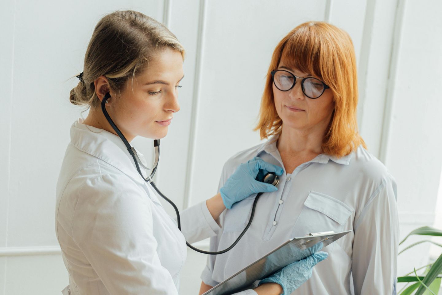 Eine Ärztin untersucht eine Patientin mit dem Stethoskop.